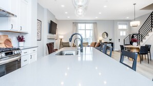 Une cuisine moderne dotée d’un îlot central, de meubles blancs et d’une hotte de cuisine en acier inoxydable.
