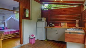 A compact kitchen with a refrigerator, microwave, and a gas stove. - Le Parc aux Orchidées (Pointe-Noire)