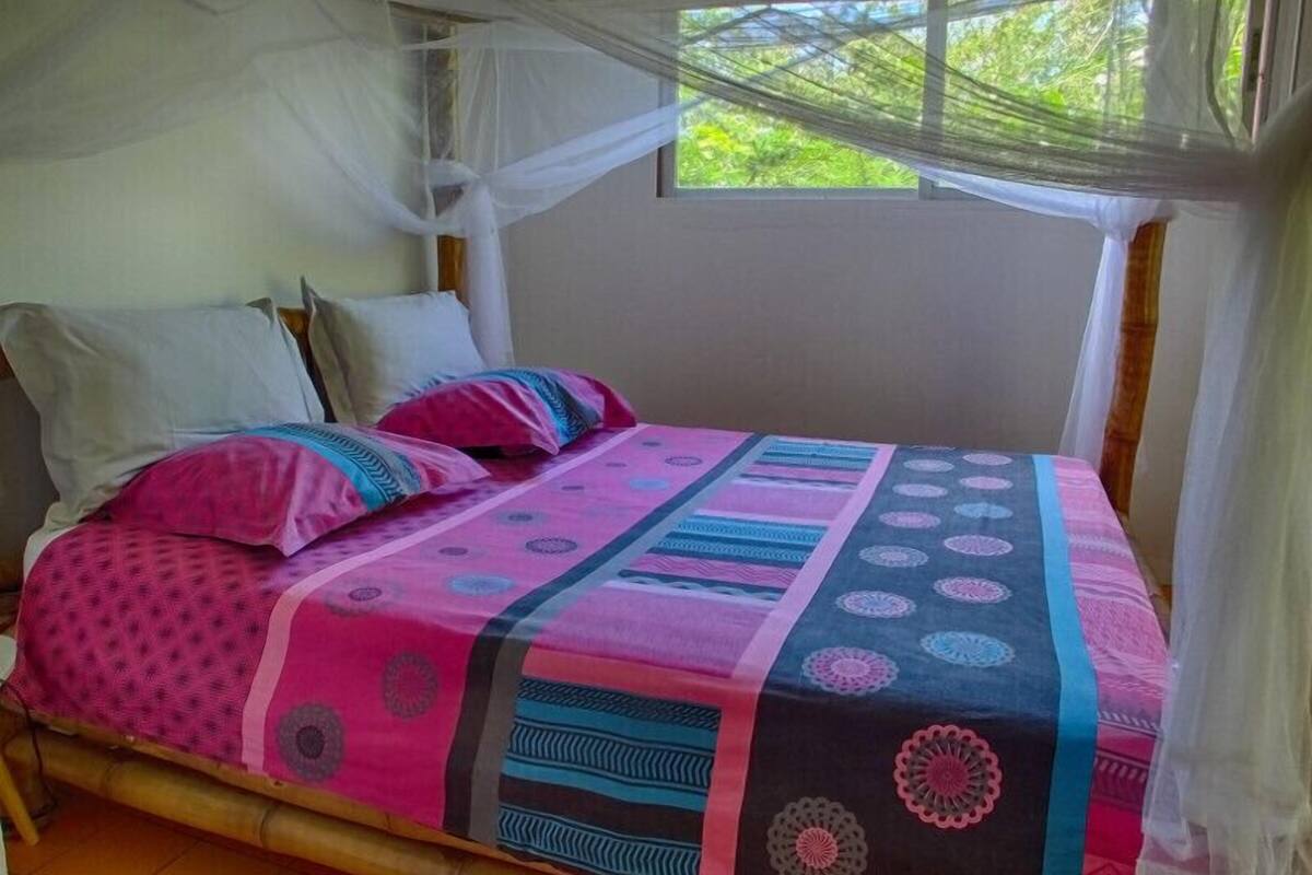 Una cama con una colcha colorida y una mosquitera.
