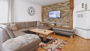 Ein modernes Wohnzimmer mit Steinakzentwand, einem Flachbildfernseher, einer Couch, einem Couchtisch und einem gemusterten Teppich.