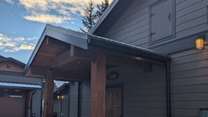 Ein modernes Haus mit einer Steinsäule, einer Garage und einer überdachten Veranda.