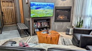 Ein modernes Wohnzimmer mit Flachbildfernseher, Kamin, Bücherregalen und bequemen Sitzmöglichkeiten.