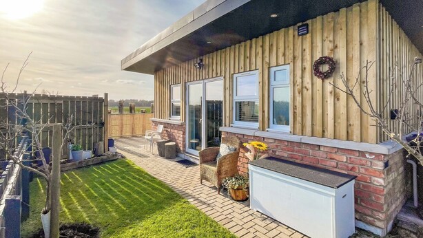 Una casa moderna con fachada de madera, ventanas amplias y un césped bien cuidado.