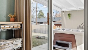 A patio area with a sliding glass door, a cushioned seating area, and a small table.