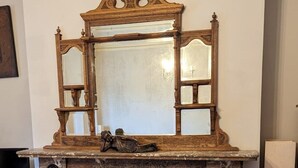 Une cheminée surmontée d’un miroir, agrémentée d’une sculpture décorative en dessous, et dotée d’un foyer recouvert de carreaux bleus.