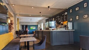 Un restaurant moderne doté d’un bar, de tables en bois et d’un mur bleu orné de tableaux.