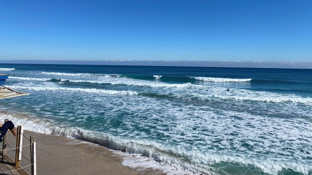 Una playa con olas y cielo despejado.