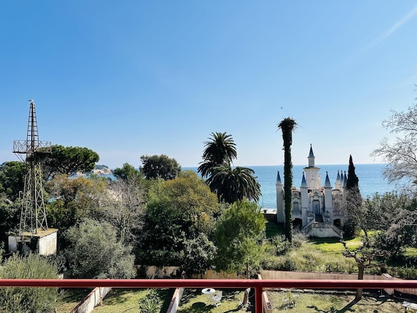 Una vista sul litorale con un edificio bianco caratterizzato da numerose guglie, immerso nel verde e sotto un cielo azzurro limpido.