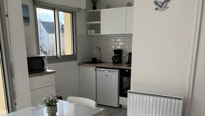 Eine kompakte Küche mit Mikrowelle, Kaffeemaschine und kleinem Kühlschrank.