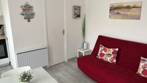 Ein Wohnzimmer mit einem roten Sofa, einem weißen Tisch mit einer Pflanze und einer Tür mit Hinweisschildern.