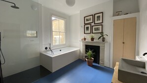 A modern bathroom with a bathtub, a shower, a window, and a fireplace. - Spacious family townhouse, Telegraph Hill, Summer '23 (London)