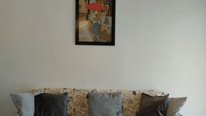 Un sofá gris con cojines estampados y un cuadro enmarcado encima.