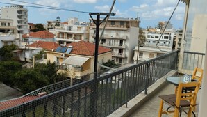 Un balcón con vista a una zona residencial, que incluye edificios con paneles solares y un jardín cercado.