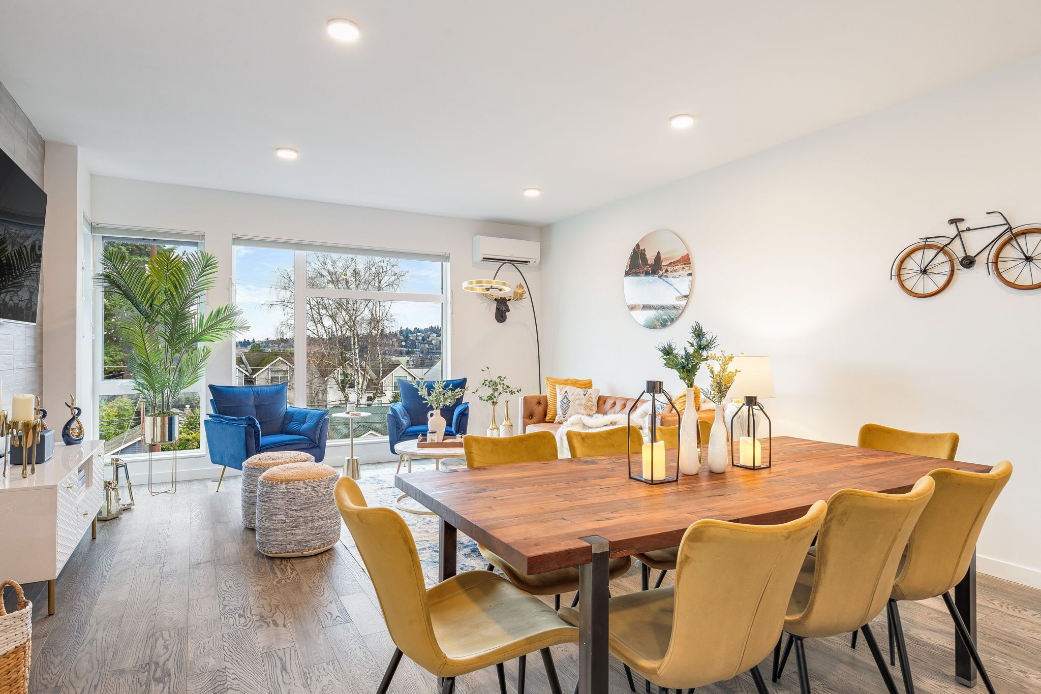 A modern dining area with a wooden table, yellow chairs, and a view of the outdoors.