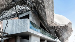 Una estructura arquitectónica moderna con un llamativo frente de vidrio curvo y un elemento grande y blanco en forma de cúpula.