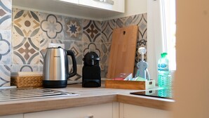 Una cocina con cafetera, hervidor y dispensador de agua en la encimera.