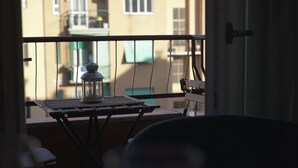 Un balcón con una mesa que sostiene un farol y una silla.