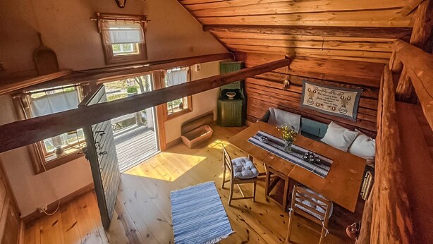 En hyggelig hytte med træpaneler, et spiseområde med bord og stole, og et lille vindue med udsigt til naturen.