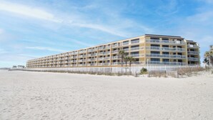A multi-story hotel with balconies, situated on a sandy beach. - Ocean Front Oasis with pool access~ Salty Sanctuary (Folly Beach)