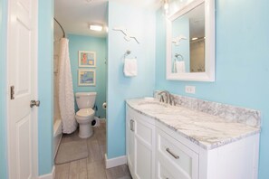 A bathroom with a toilet, shower, and sink with marble countertop. - Ocean Front Oasis with pool access~ Salty Sanctuary (Folly Beach)