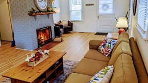 A living room with a fireplace, a sofa, a coffee table, and a door. - Riverside cottage, minutes from historic Harpers Ferry!  Private river access! (Harpers Ferry)
