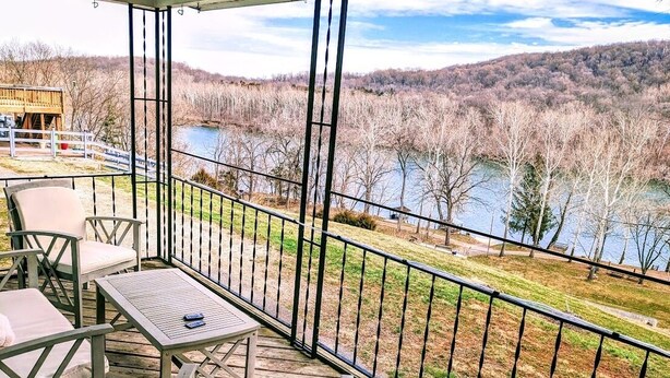 A wooden deck with outdoor furniture, a table, and chairs overlooking a river and forested area. - Riverside cottage, minutes from historic Harpers Ferry!  Private river access! (Harpers Ferry)