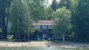 Ein Haus mit Balkon, umgeben von Bäumen in der Nähe eines Gewässers.