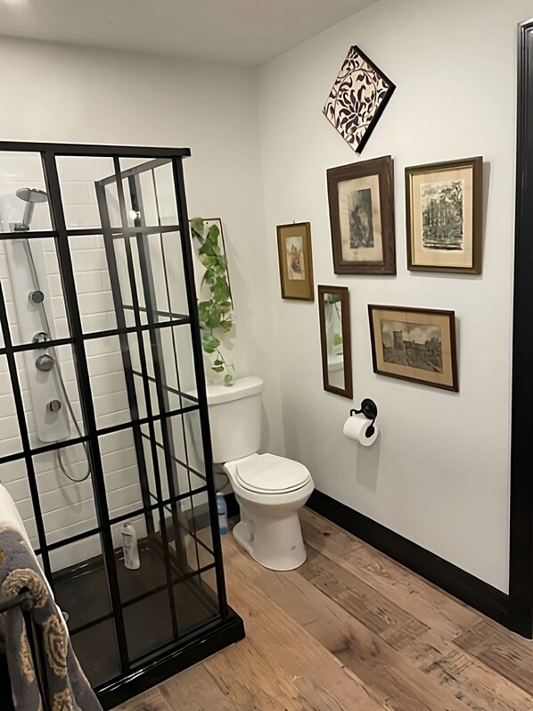 Un baño con cabina de ducha, inodoro y soporte de papel higiénico en la pared.