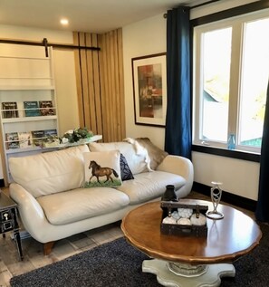 A modern living room with a white leather sofa, a wooden coffee table, and a bookshelf.