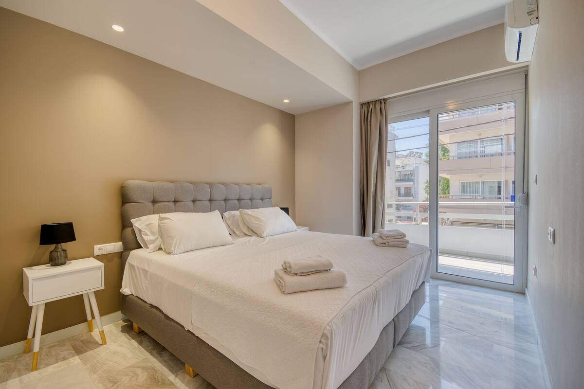 A bedroom with a bed, bedside table, and a view of the outside.