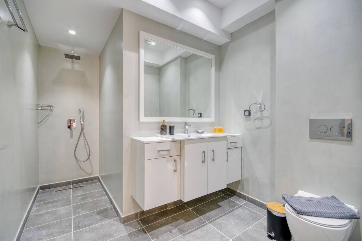 A modern bathroom with a walk-in shower, a large mirror, and a toilet with a towel on top.