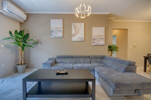 Una sala de estar moderna con un sofá seccional gris, una mesa de centro negra y tres cuadros en la pared.