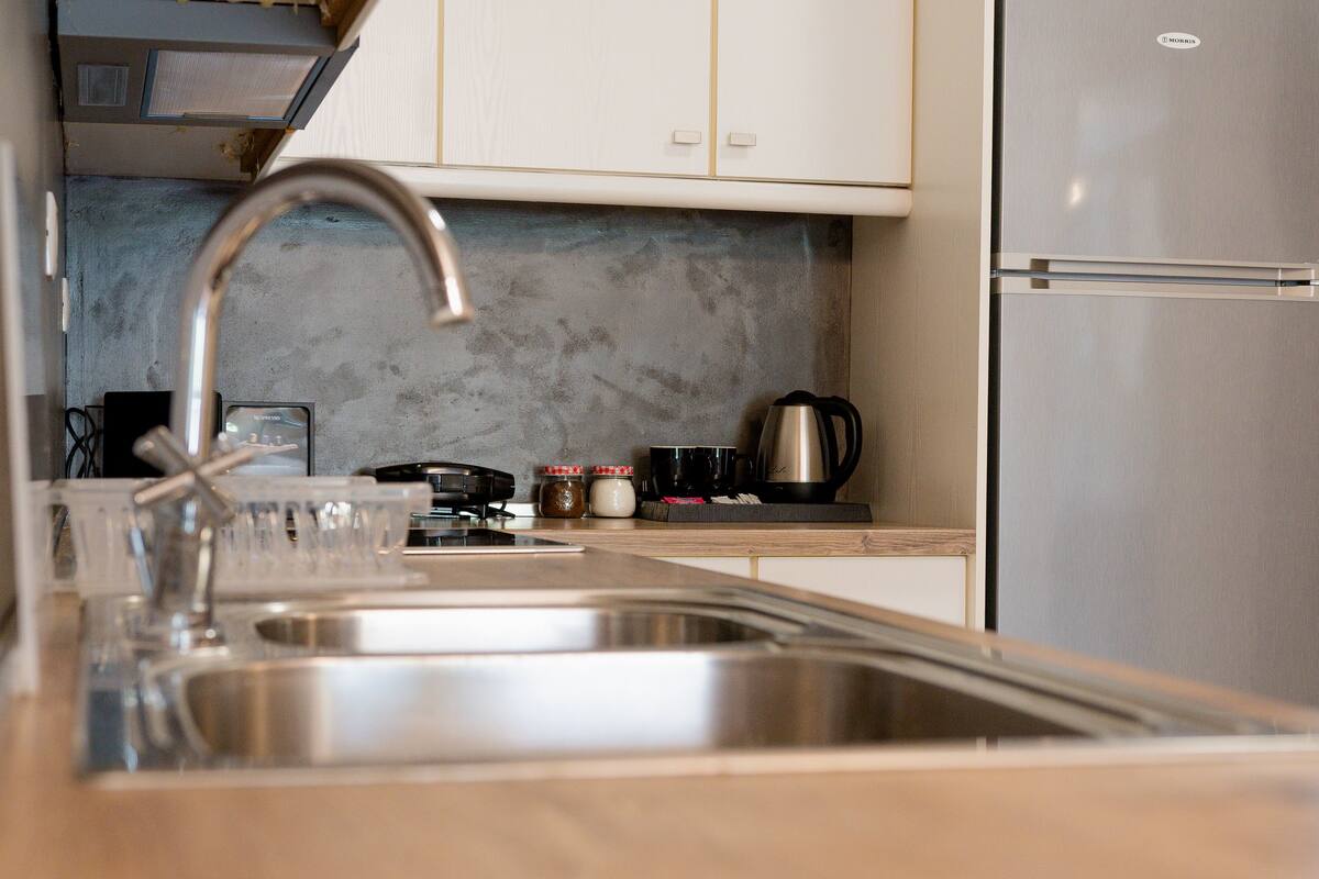 A kitchen with stainless steel appliances, a sink, and a countertop with various items.