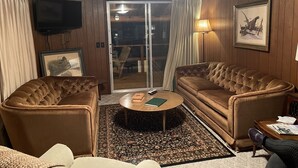 A cozy living room with a brown leather sofa, two armchairs, a coffee table, and a television. - Cozy Cottage Five (Florien)