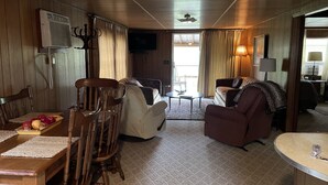 A cozy living room with a wooden ceiling, a dining table with chairs, a sofa, and a television. - Cozy Cottage Five (Florien)