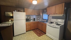 A kitchen with wooden cabinets, a refrigerator, a microwave, a stove, and a sink. - Cozy Cottage Five (Florien)