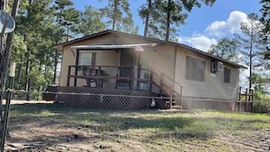 A single-story cabin with a porch, a small deck, and a fenced yard. - Cozy Cottage Five (Florien)