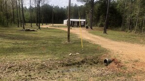 Un terrain de camping comprenant une seule cabane, un chemin de terre et une zone herbeuse.