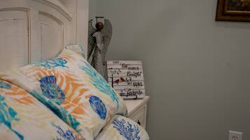 A bed with a floral patterned bedspread, a decorative angel figurine, and a sign with a quote on a bedside table.