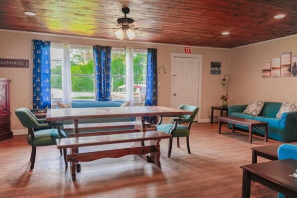 Una habitación con una mesa y sillas de madera, un sofá y una ventana con cortinas.