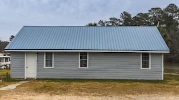 Simple, single-story residence with a gabled roof and a grassy lawn.