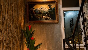 Una escalera con un cuadro en la pared, una planta en maceta y una pared con textura.