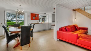 A modern kitchen with white cabinets, a red sofa, and a dining area with a wooden table and chairs. - Stunning home in Grenaa with WiFi (Grenaa)