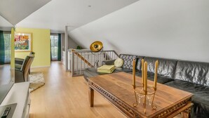 A modern living room with a wooden coffee table, a black leather sofa, and a staircase leading to an upper level. - Stunning home in Grenaa with WiFi (Grenaa)