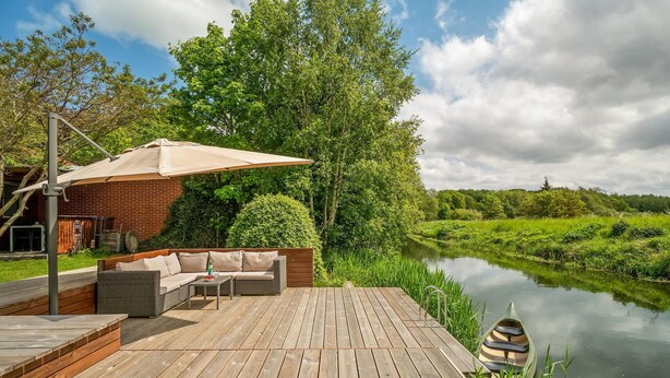 A wooden deck with outdoor furniture, a covered seating area, and a river view. - Stunning home in Grenaa with WiFi (Grenaa)