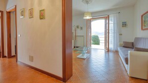 Un amplio salón con un sofá, una mesa de centro de vidrio y vistas al exterior.