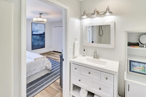 A modern bathroom with a white vanity, a large mirror, and a ceiling light fixture.