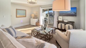 A modern living room with a glass coffee table, a sofa, a dining table, and a large window with a view.