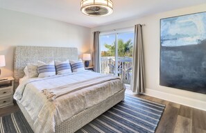 Relax in this serene bedroom with a large bed, bedside table, and a window offering a view of the balcony.