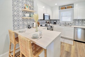 Una cocina moderna con armarios blancos, una isla central y un salpicadero con diseño.